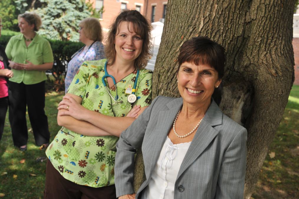 A group of Nurses post outside next to a tree.